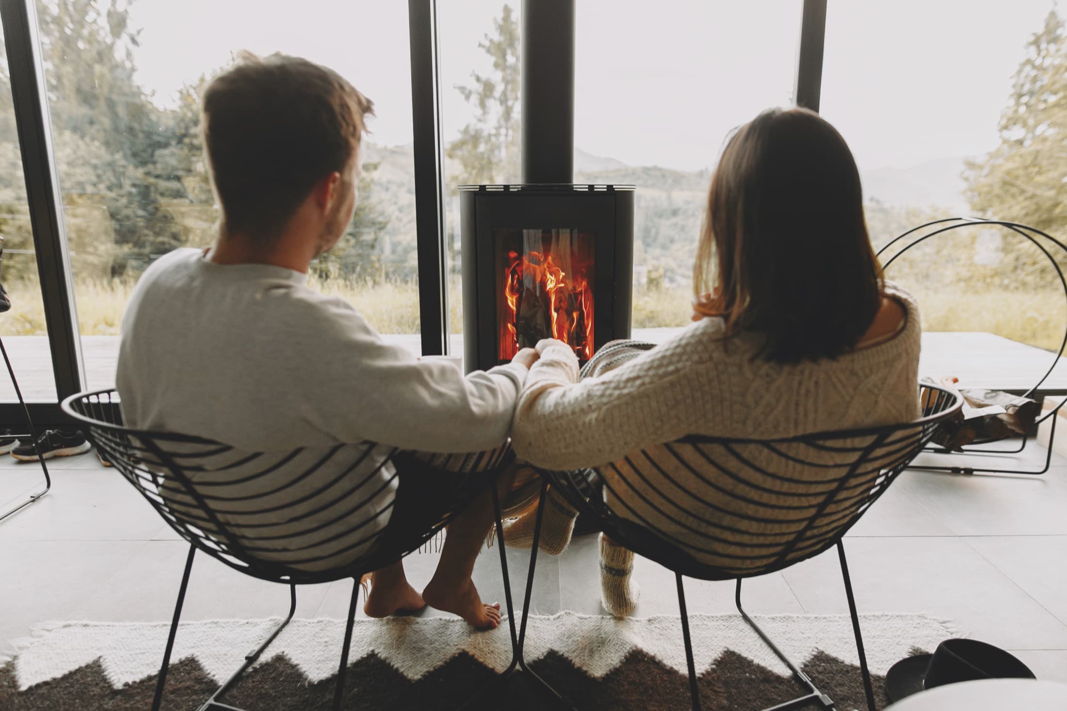 A couple relaxing by the fireplace in a cozy short-term rental